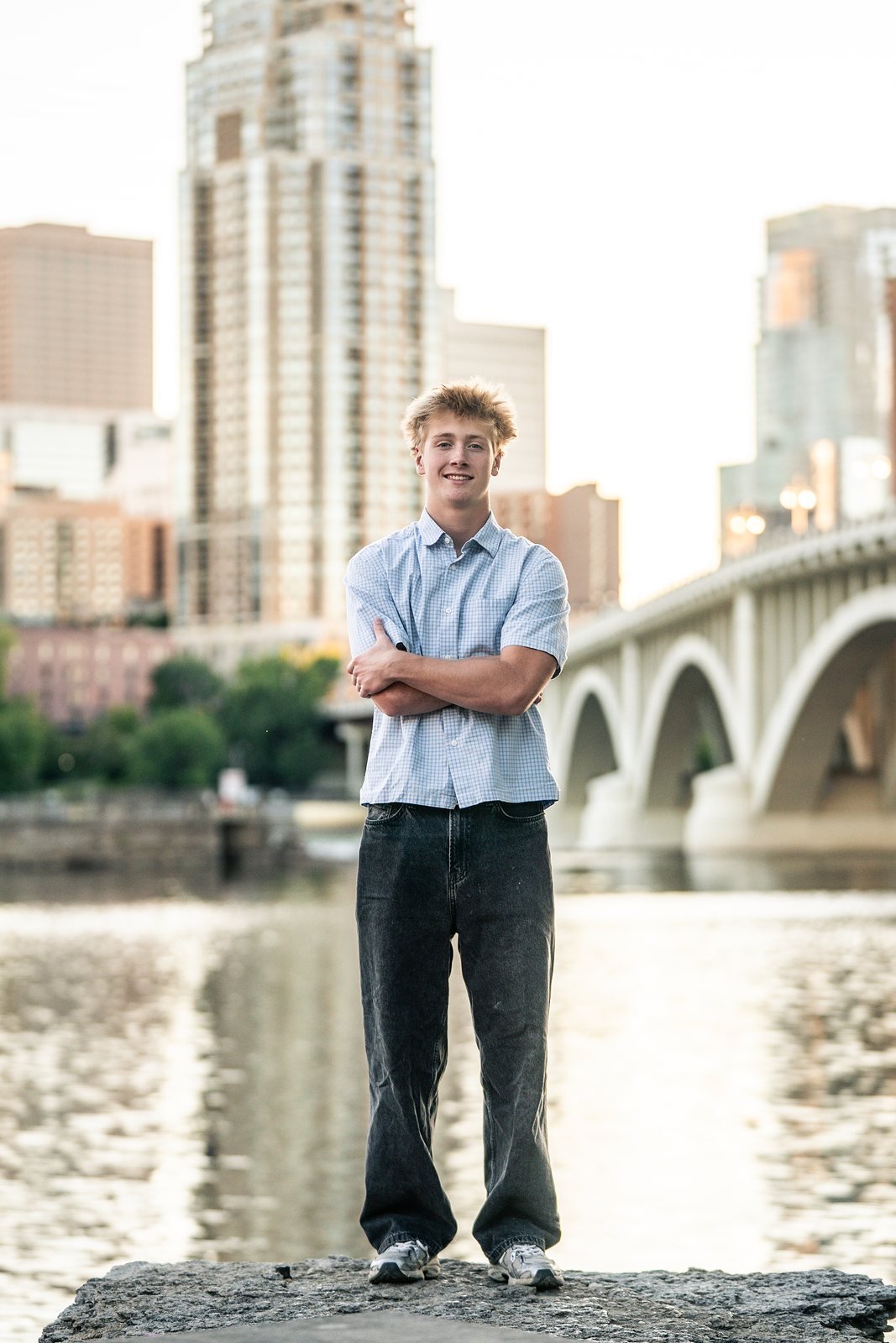 Senior portrait by the river with the Minneapolis skyline behind