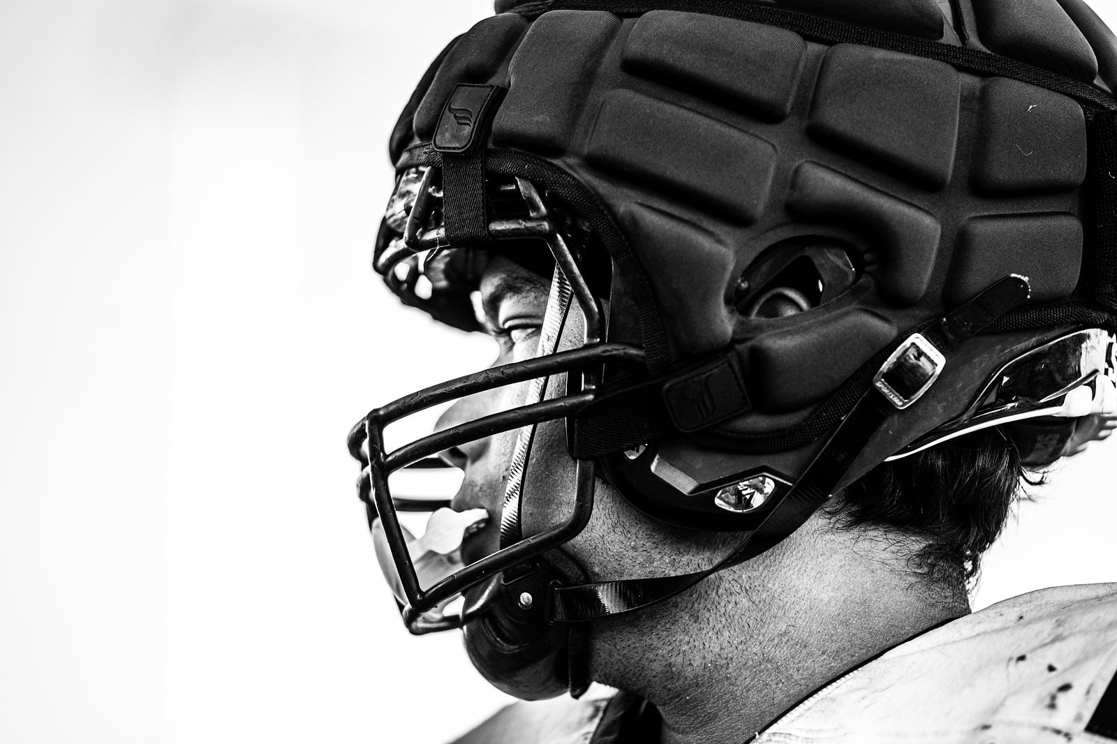 Black and white close-up profile of a player in a padded football helmet