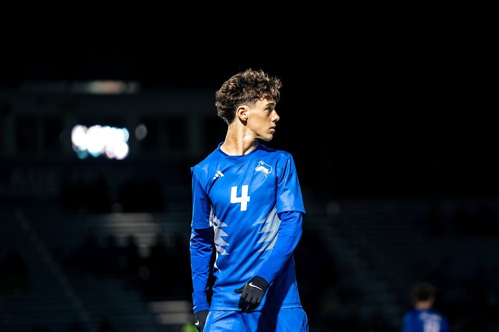 Soccer player in a bright blue kit under stadium lights